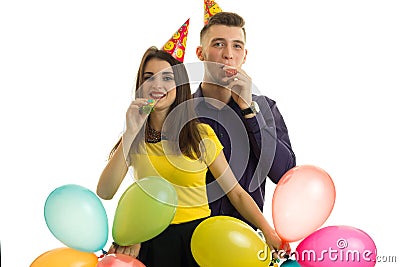 Beautiful couple in love with cones on their heads carrying balloons and blow horns isolated on a white background Stock Photo