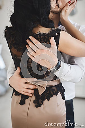 Beautiful couple in love hugging and kissing in the interior. Sexy brunette model girl in skirt and blouse hugging with Stock Photo