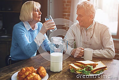 Beautiful couple are sitting at the table in the kitchen and dri Stock Photo