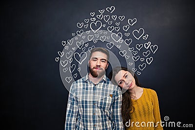 Beautiful couple standing over black board with drawn hearts Stock Photo