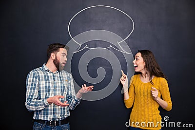 Beautiful couple talking over blackboard background with speech bubble Stock Photo