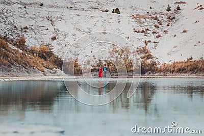 Beautiful couple walking in the phosphate-gypsum white mountains of Ukraine, the girl in a red dress on a background of a green Stock Photo