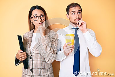 Beautiful couple wearing business clothes drinking take away coffee holding folder serious face thinking about question with hand Stock Photo