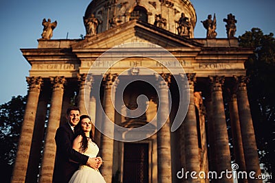 Beautiful couple in wedding dress outdoors near antique victorian church Stock Photo