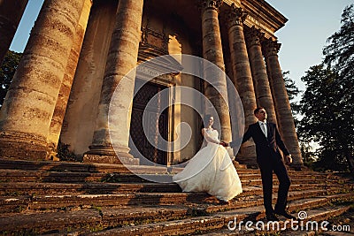 Beautiful couple in wedding dress outdoors near the victorian church Stock Photo