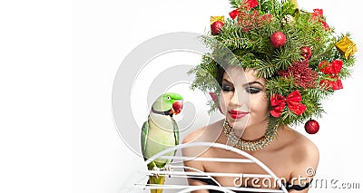 Beautiful creative Xmas makeup and hair style indoor shot. Beauty Fashion Model Girl with green parrot Stock Photo