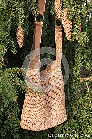 Beautiful crocheted hand made brown handbag between the spruce cones on the tree Stock Photo