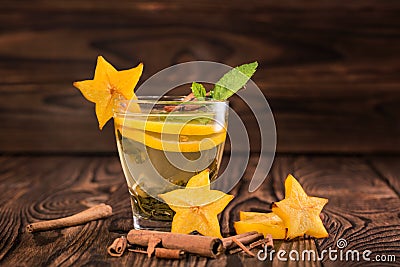 Beautiful cup of tea. Green tea on a wooden background. Mint tea with lemon, decorative carambola, cinnamon. Copy space. Stock Photo