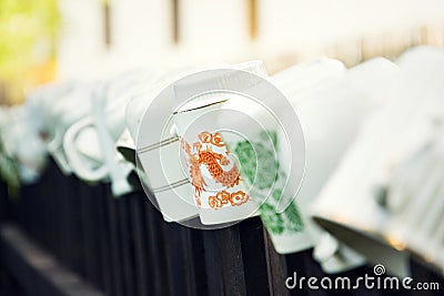 Beautiful cups laid upside down on wooden fence bars for wanderers refreshment, Asian dragon ornament, peace meditation wanderlust Stock Photo