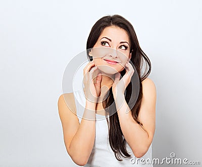 Beautiful curious smiling woman with amazing eyes holding the head the hands thinking and looking up in casual white t-shirt and Stock Photo