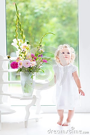 Beautiful curly baby girl with fresh flower bouquet Stock Photo