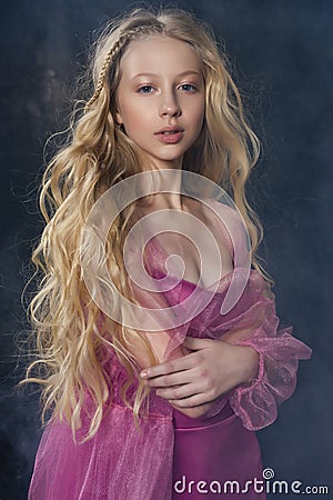 Beautiful curly blonde teenager child girl wearing a pink air dr Stock Photo