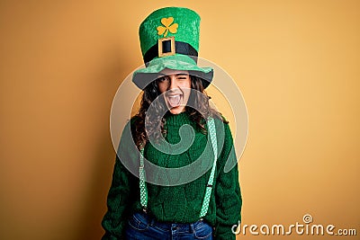 Beautiful curly hair woman wearing green hat with clover celebrating saint patricks day winking looking at the camera with sexy Stock Photo