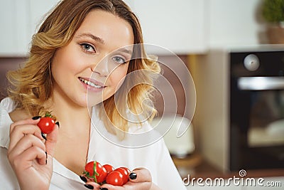 Beautiful curly haired girl holding cherry tomatoes Stock Photo