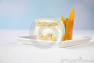 Beautiful cut of a piece of mousse cake on a white plate on the table - the cut shows mousse, icing, sponge cake, vanilla, fruit Stock Photo