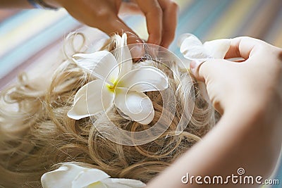 Beautiful, cute blond bride doing hair with flowers before wedding day. Long lashes, white flowers, smilling and happy. Stock Photo