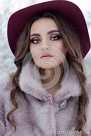 Beautiful cute elegant girl in a fur coat and hat walking in the winter forest bright frosty morning Stock Photo
