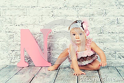 Beautiful and cute girl in pink dress with the letter N. Emotional girl. Stock Photo