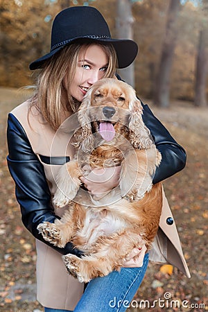 Beautiful cute happy girl in a black hat playing with her dog Stock Photo