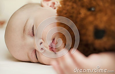 Cute little baby sleeping in a sweet sleep hugging a bear Stock Photo