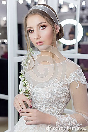 Beautiful cute tender young girl bride in wedding dress in mirrors with evening hair and gentle light make-up Stock Photo