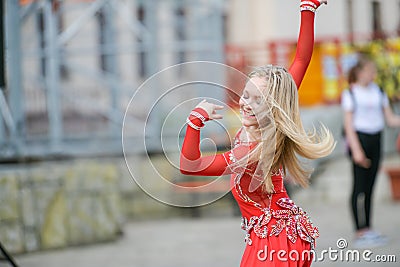 Beautiful dancer in a red dress. Beautiful young girl dancing in a red dress. Dance in public. Talented kid does dancing Editorial Stock Photo