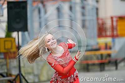 Beautiful dancer in a red dress. Beautiful young girl dancing in a red dress. Dance in public. Talented kid does dancing Editorial Stock Photo