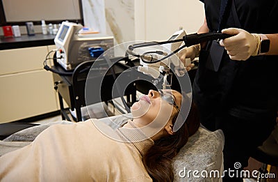 Beautiful dark-haired Hispanic woman getting laser skin resurfacing procedure in wellness spa clinic. Hardware cosmetology Stock Photo