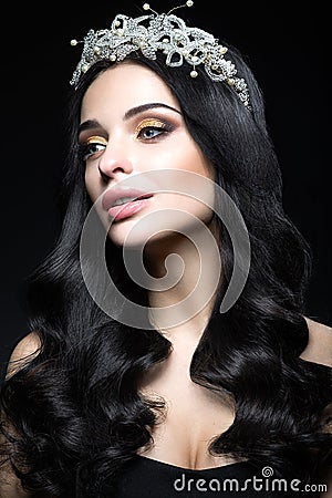 Beautiful dark-haired woman with a crown of precious stones, curls and evening makeup. Beauty face. Stock Photo