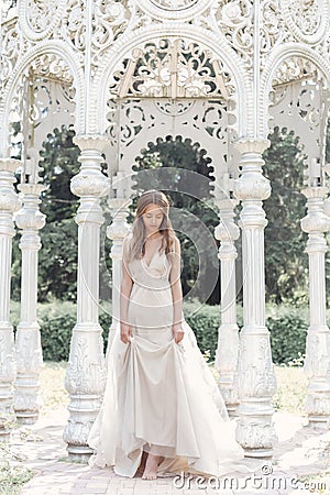 Beautiful delicate bride girl in a light beige wedding dress walks in the garden bright sunny warm day Stock Photo