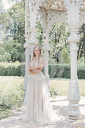 Beautiful delicate bride girl in a light beige wedding dress walks in the garden bright sunny warm day Stock Photo