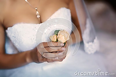 Beautiful delicate wedding boutonier with pink flowers in the hands of the bride, lace dress and veil, morning of the bride Stock Photo