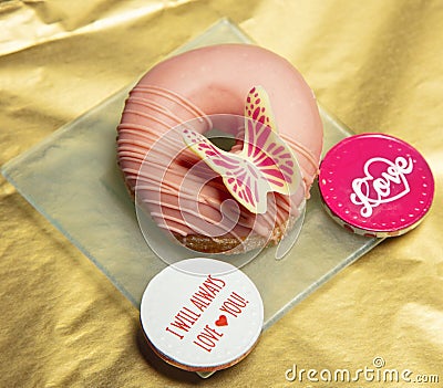 Beautiful donut covered with pink chocolate and decorated with a beautiful butterfly , view from above Stock Photo