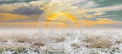 Beautiful dramatic landscape of the transitional season snow-covered field at sunset Stock Photo