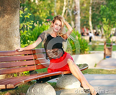 Beautiful dreamy woman on bench in city park in summer Stock Photo