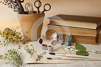 Beautiful dried flowers, books, brushes and paints on wooden table Stock Photo