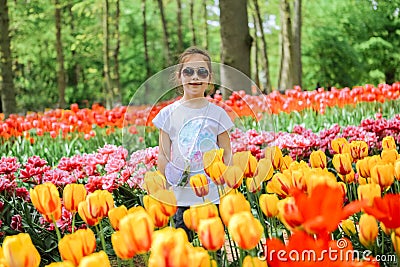 Beauriful dutch girl smelling tulip flower on tulip fields. Child in tulip flower field in Holland. Kid in magical Netherlands Stock Photo