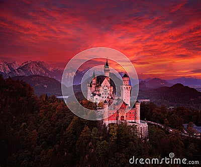 Beautiful early morning view of the Neuschwanstein fairy tale castle, bloody dark sky with autumn colours in the trees during Stock Photo