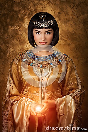 Beautiful Egyptian woman like Cleopatra with magic ball on golden background Stock Photo