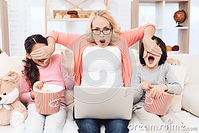 Beautiful elderly grandmother watching horror film on laptop with her grandchildren together. Stock Photo
