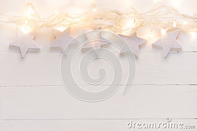 Beautiful elegant Christmas New Year background. White stars sparkling golden lights garland on plank wood. Upper border Stock Photo