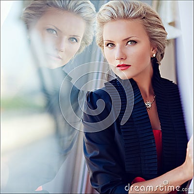 Beautiful elegant exquisite blonde girl looks straight and strictly, reflected in the glass Stock Photo