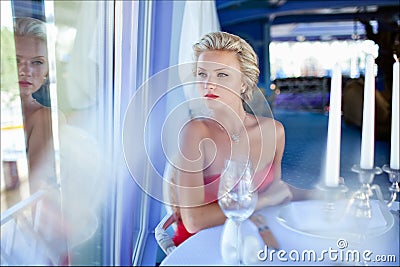 Beautiful elegant exquisite blonde girl in red dress sitting at Stock Photo