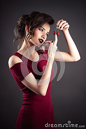 Beautiful elegant girl in red dress with cherry in hands Stock Photo