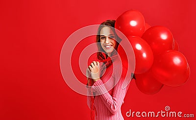 Beautiful emotional girl in pink dress with red ballons on red background Stock Photo
