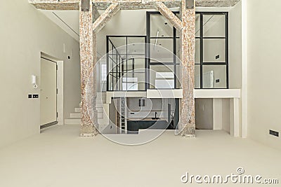 A beautiful empty loft with an old structure of wooden beams and pillars, Stairs made of polished white concrete with access to a Stock Photo