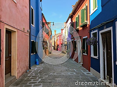 A beautiful empty narrow shaded cobblestone street with an array of old colourful square homes on the small island of Burano Editorial Stock Photo