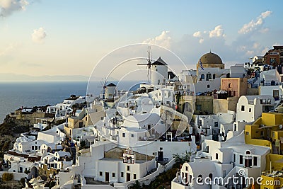 Beautiful evening light scene of Oia white building townscape and windmill along island mountain, vast ocean, soft cloud Editorial Stock Photo