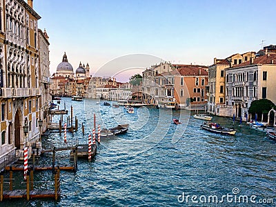 A beautiful evening view of the Grand Canal in Venice, Italy with water taxis and gondolas past by and the Santa Maria Della Salut Stock Photo