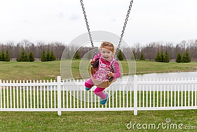 Beautiful excited little girl on a swing Stock Photo